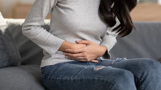an image of a women who is holding her lower abdomen as she is in pain and suffering from a uti or bladder infection
